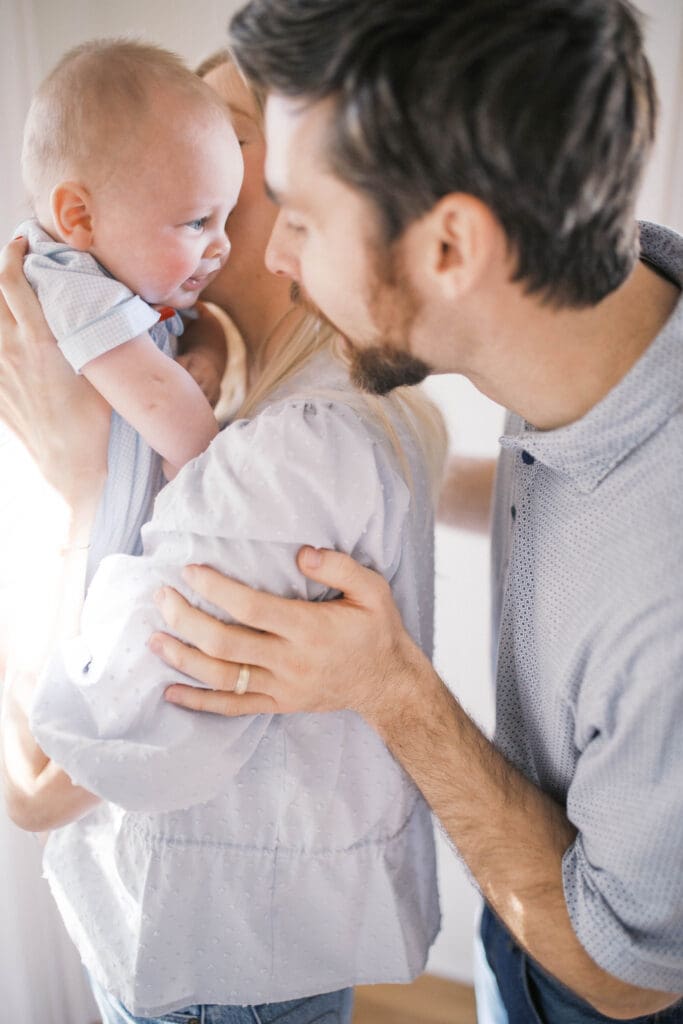Lifestyle Newborn Photo of a mom in blue jeans and dad dancing with baby boy in the sitting room
