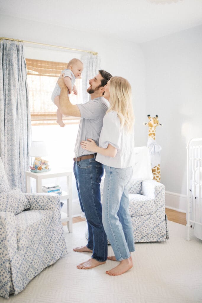 Lifestyle Newborn Photo of a mom in blue jeans and dad tossing baby boy in the air shot in a Jacksonville Home in the nursery