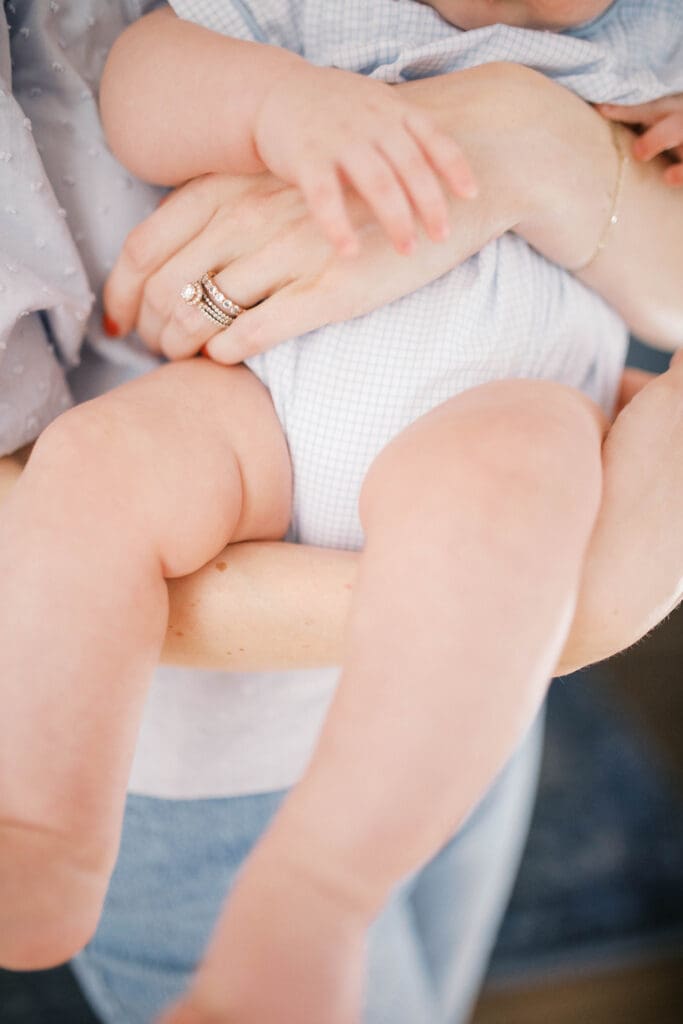Lifestyle Newborn Photo of baby and mom's arm & leg intertwined as he is perched on her arm