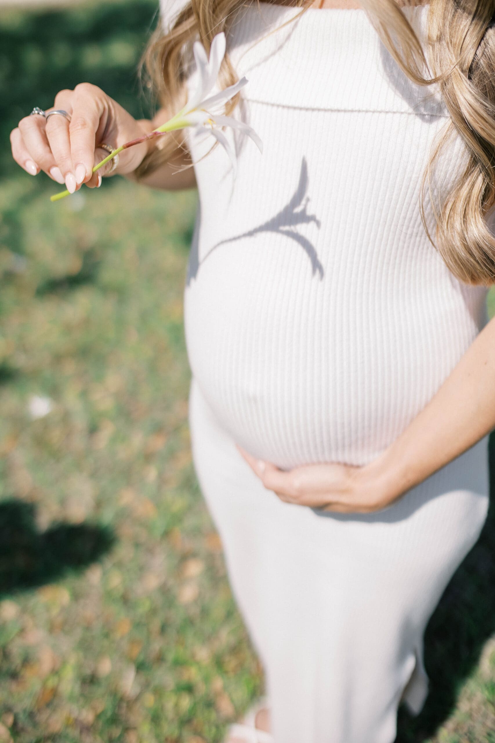 New mother cuddling her baby bump during an outdoor maternity photography session in Jacksonville, Florida.
