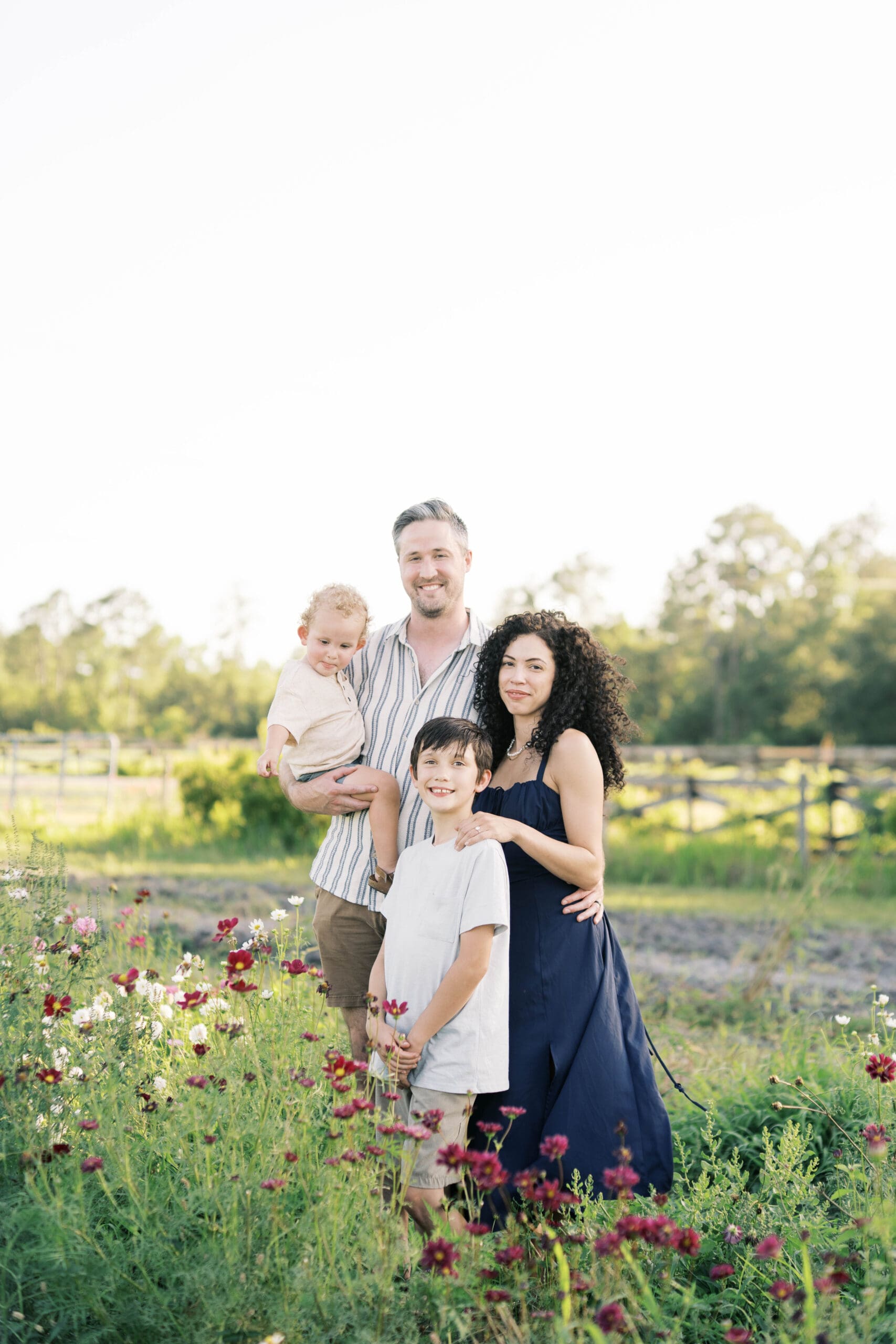 Family portrait of a mom dad toddler boy and older brother standing in a field of flowers in St Augustine, FL