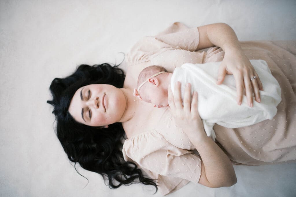 Jacksonville newborn photos featuring mom resting peacefully with baby during timeless family portrait session