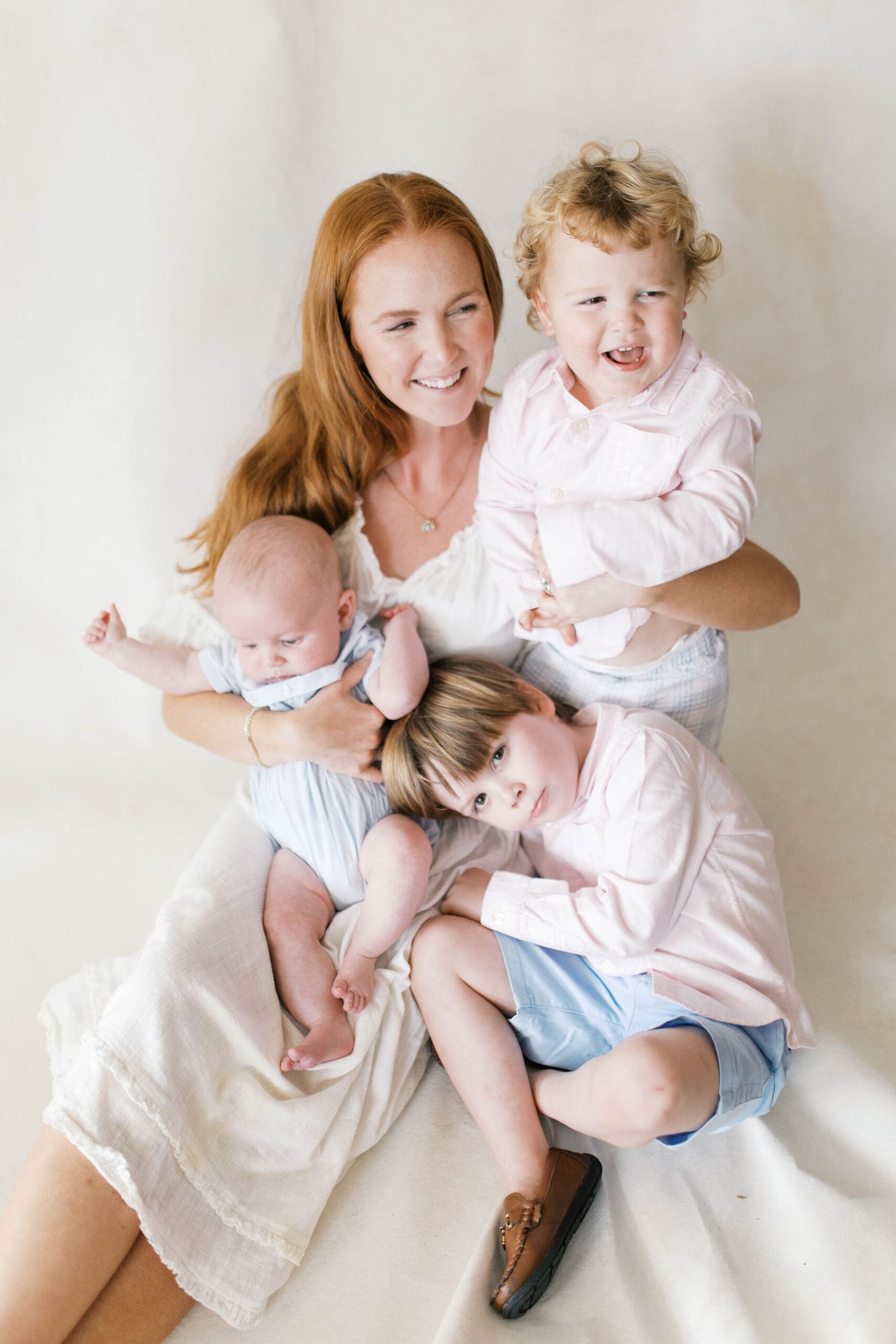 Family portrait of a young redhead mother of 3 boys playing and laughing together in a studio in Jacksonville