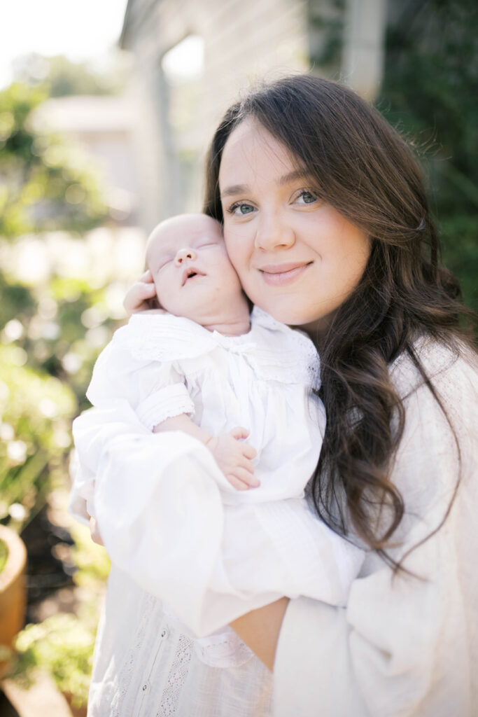 mom smiling as she holds her baby to her cheek during in home newborn portrait session 