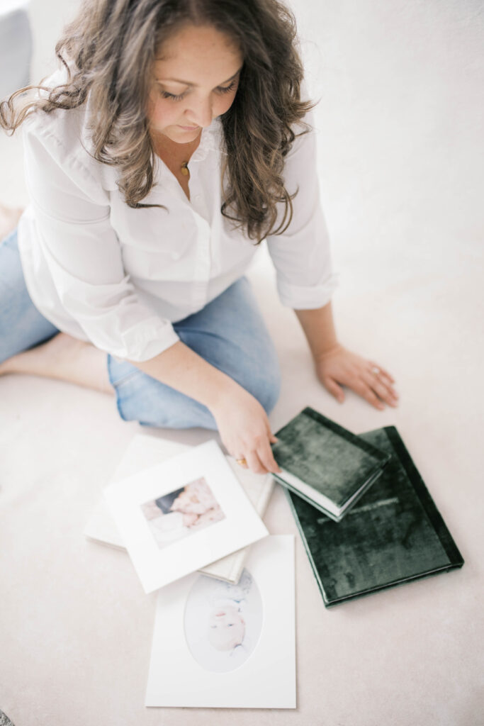 Jacksonville newborn photographer looking through a custom velvet album for a client