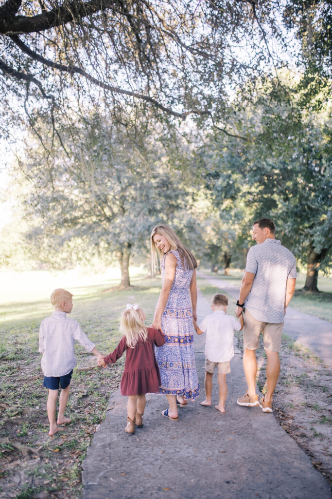 family all holding hands walking away from camera smiling at one another